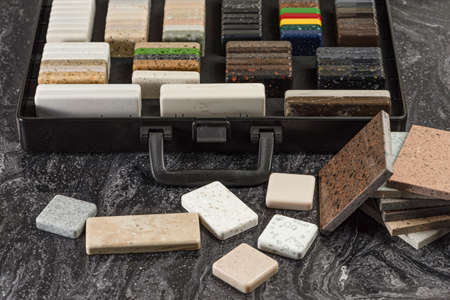 Large selection of stone samples for countertops and floors. Pieces of artificial acrylic stone in a sample box. A set of shades of countertops of different texturesの写真素材