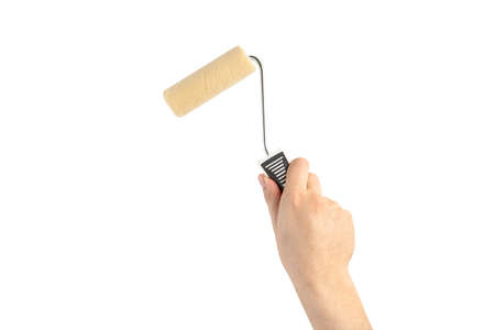 Paint roller in a mans hand. Renovation concept. Supplies and tools for painting walls isolated on whiteの写真素材