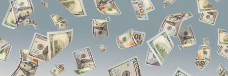 One hundred dollar bills are falling against a blue background. The concept of wealth, big wins or...