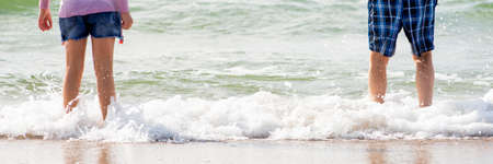 Rest by the sea. Children stand in the water on the beach in the hot summer. Children have fun by the seaの写真素材