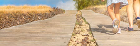 Wooden path in the mountains. Winding tourist path made of boards in the mountains. Mom and daughter...