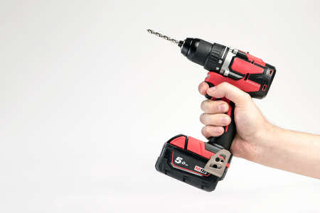 Cordless drill in black and red. Screwdriver with a drill in hand on a white background. Modern...