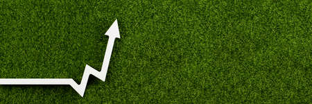 White chart arrow on green grass points up. Business development symbol, ecology concept, green energy.の写真素材