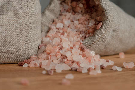 Salt price. Large crystals of pink Himalayan salt, close-up. A coin in a pile of salt as a symbol of...