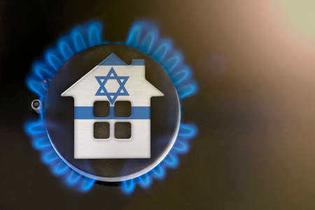 Heating season Israel. The beginning of the heating season on natural gas. Concept, model of a house stands near the flame of a gas boiler on a black background. Israel home heating cost.の写真素材