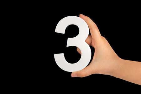 number three in hand isolated on black background. Number three in a childs hand on a black...