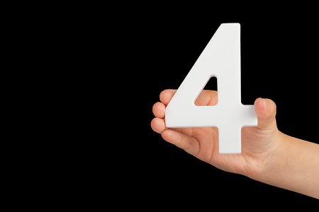 Number four in hand isolated on black background. Number four in a childs hand, holding on a black background. To be inserted into a project or design.の写真素材