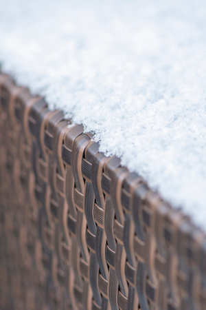 Care and storage of garden furniture in winter. texture of street furniture in winter. Artificial rattan covered with snow close-up.の写真素材
