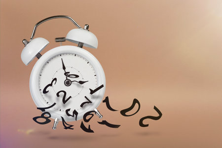 Time is running out. White alarm clock with flying numbers as a symbol of lost time. The concept of...
