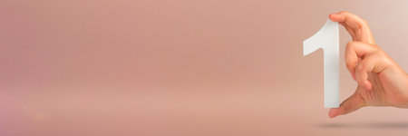 Number one in hand. A hand holds a white number one on a red background with copy space. Concept with number one. 1 percent rate, birthday, first or winner.の写真素材