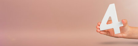 number four in hand. Hand holding white number 4 on red background with copy space. Concept with number four. Birthday 4 years, fourth grade, four day work weekの写真素材