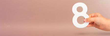 Eight in hand. A hand holds a white number 8 on a red background. Concept with number eight. Birthday 8 years, percentage, eighth grade or day, international womens day.の写真素材