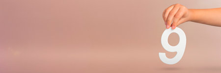 Number nine in hand. A hand holds a white number 9 on a red background. Concept with number nine. Birthday 9 years, percentage, ninth grade or day.の写真素材