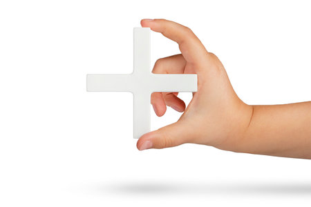 White plus symbol in hand. The concept of social security, and health insurance. Personal development, growth concept. Mathematical symbol plus of white color in a hand on a white isolated backgroundの写真素材