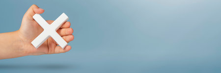 White multiplication symbol or cross in hand. The concept of prohibition or removal. Mathematical white symbol multiply in hand on a blue backgroundの写真素材