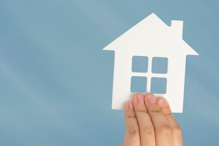 Buying real estate on credit. Model of a white house in hands on a blurred background. Buy a house or apartment, mortgage real estate concept, with copy spaceの写真素材