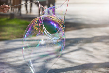 A man makes a huge soap bubble in the park. Summer fun in the park for the whole family.の写真素材