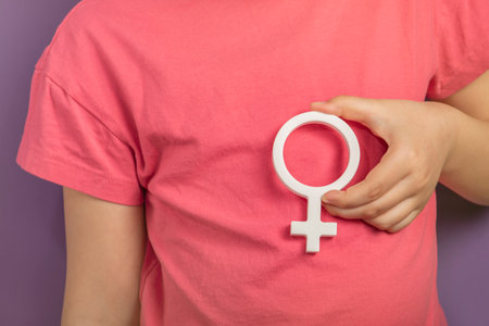 Gender symbol of a woman. Banner with woman symbol in hands on purple background with copy space. The concept of female discrimination, leadership or domestic violence protest.の写真素材