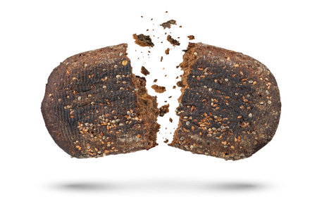 Loaf of black bread on a white isolated background. The bread is broken into 2 parts, crumbs are pouring out of it. Bottom view.の写真素材