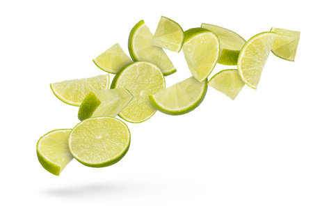 Flying fruits. Lime slices on a white isolated background. Lime slices scatter in different directions, casting a shadow, close-up. Suitable for advertising banner. High quality photo.の写真素材