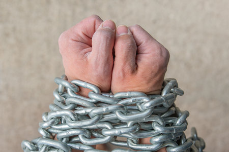 The workers hands are wrapped in a chain as a concept of slavery or dependence on something....
