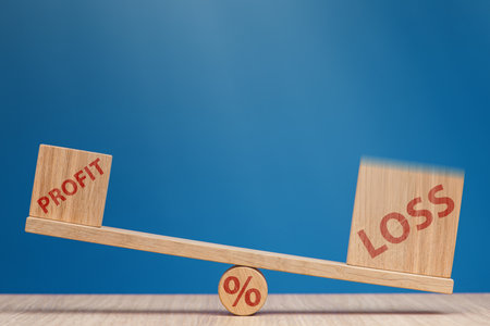 Increasing losses in the stock market. Loss and profit on the scales on a blue background. Loss of investment in stock exchange, bear market and recession concept.の写真素材