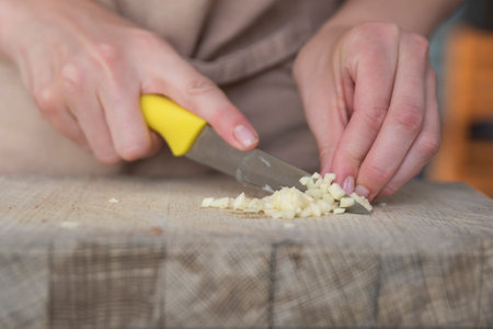 A woman cuts garlic with a knife close-up. Cutting garlic for salad or as an aromatic spice for meat.の写真素材