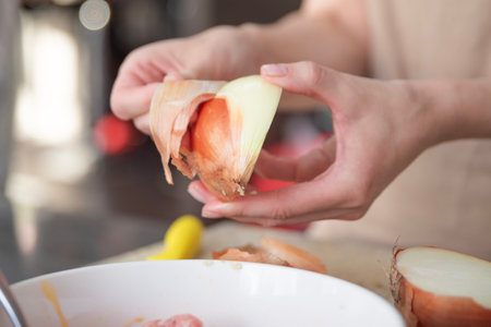 A womans hands peel an onion into slices, close-up. The process of cooking onions as a dressing.の写真素材