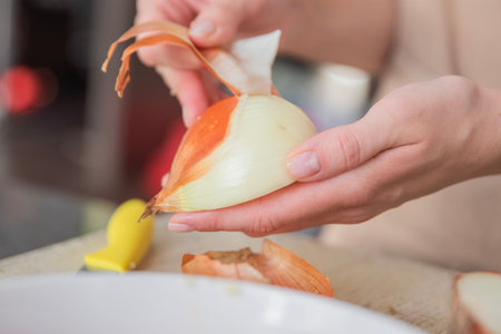A womans hands peel an onion into slices, close-up. The process of cooking onions as a dressing.の写真素材