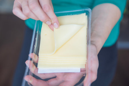Hand holding mozzarella cheese close-up. The process of preparing sandwiches. A quick snack in the form of cheese.の写真素材