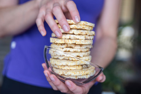 A hand holds a bowl of corn chips close-up. The process of eating a quick snack in the form of corn chips.の写真素材