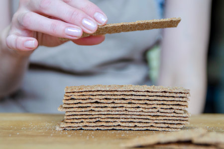 A woman's hand holds a piece of bread close-up. Sorting a small snack in the form of bread.