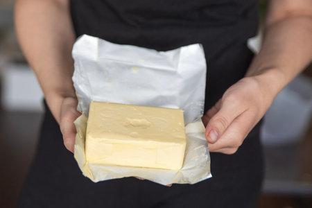 A hand holds butter in a pack close-up. Process of making sandwiches with butter.の写真素材