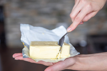 A hand holds butter in a pack close-up. Process of making sandwiches with butter.の写真素材