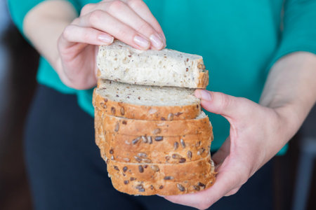 Womans hands holding slices of bread close-up. The process of preparing fresh sandwiches.