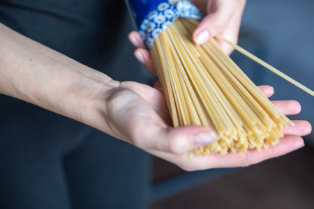 Hand holding spaghetti close-up. The process of cooking Italian spaghetti.の写真素材