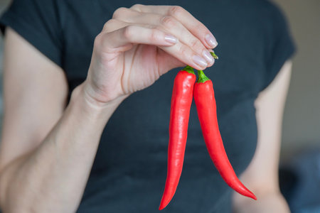 Womans hand holding chili pepper close-up. The process of preparing spicy soup or homemade hot sauce.の写真素材