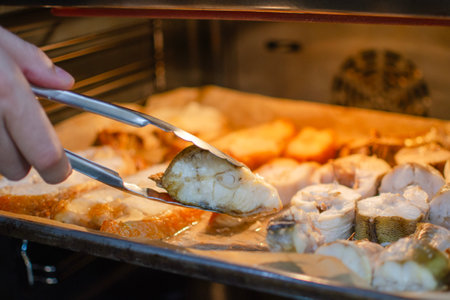 The process of preparing fish at home. Homemade baked goods in the shape of fish. A hand smears a...