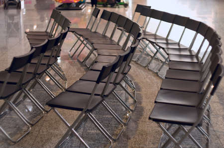 Black plastic and metal seats on the shine floor are are semicircle near the stage.の写真素材