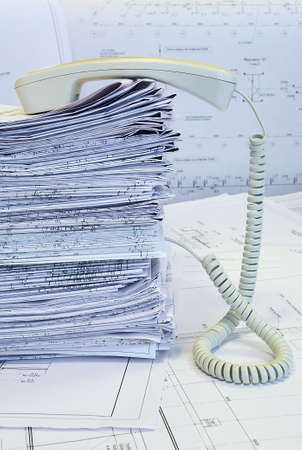 White handset on the heap of project drawings. White whatman are background. Extraordinary phone.