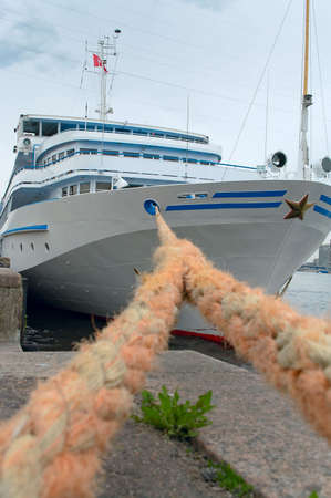 White cruise ship is moored to pier by tie-down cable.の写真素材