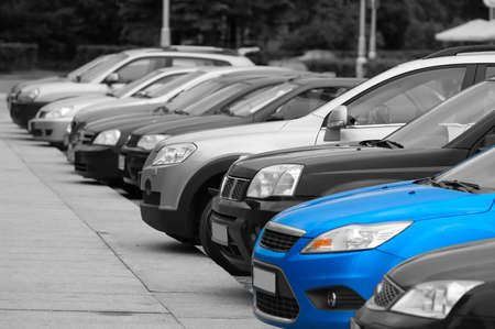 Black-and-white cars are on the parking and only one blue colored automobile.の写真素材
