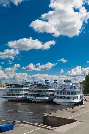 Several white cruise liners are moored in river port. Saint-Petersburg, Neva river. Blue sky with clouds.の写真素材