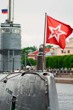 Russian diesel submarine with red fllag, hammer and sickle. Boat moored in Saint-Petersburg port.の写真素材