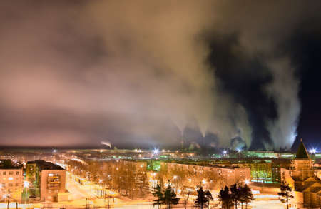 Smoke from chimneys over a town at nighttime. Night scene. Long exposure.の写真素材