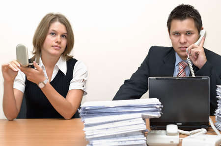 The caucasian working man and the young lazy woman sit at a table at office. On white background.の写真素材