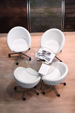 Four white chairs and glass round table in room. Interior of speaking placeの写真素材