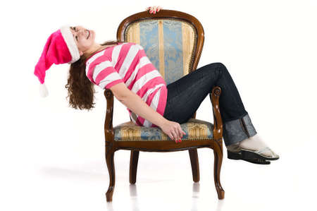 Young woman lies on chair in santa`s hat. She is smiling. Studio shot.の写真素材