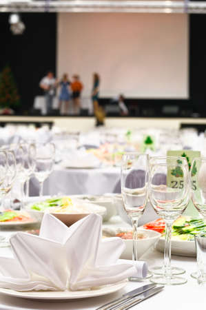 Details of a wedding banquet table setting with background of stage and people the artists.