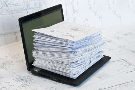 Laptop and stack of project drawings on it. Working place. 
